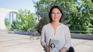 17.06.2021, Berlin: Annalena Baerbock, Kanzlerkandidatin und Bundesvorsitzende von Bündnis 90/Die Grünen, hält am Ende der Vorstellung ihres Buches «Jetzt. Wie wir unser Land erneuern» ein Exemplar in den Händen. Im Hintergrund links ist das Bundeskanzleramt zu sehen. Foto: Christoph Soeder/dpa +++ dpa-Bildfunk +++