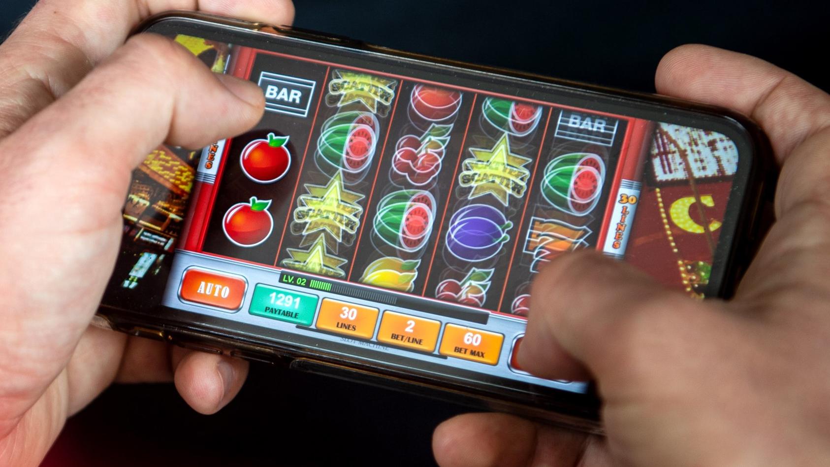 23.06.2021, Bremen: ILLUSTRATION - Auf einem Smartphone wird ein Online-Spiel gespielt. Mit dem neuen Glücksspielstaatsvertrag der am 1. Juli in Kraft tritt, werden bisher verbotene virtuelle Automatenspiele im Internet sowie Online-Casinos mit Poker