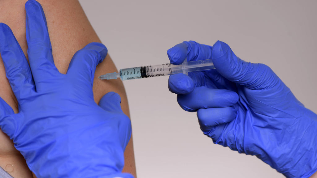 Ein Arzt injiziert einem Patienten eine Impfung.