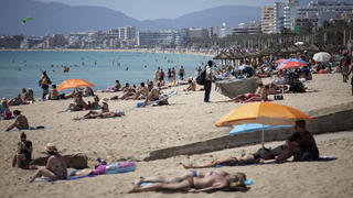 07.06.2021, Spanien, Mallorca: Touristen genießen die Sonne an einem Strand auf der spanischen Insel Mallorca. Landesweit startet die Sommertourismus-Saison mit coronabedingten Einschränkungen. Einreisende müssen vollständig geimpft sein oder, wenn sie aus Europa kommen, einen aktuellen negativen Corona-Test vorweisen. Foto: Francisco Ubilla/AP/dpa +++ dpa-Bildfunk +++
