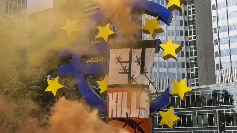 Zwei Aktivisten der Seebrücke mit Rauchbomben auf dem besetzten Eurozeichen am Willy-Brandt-Platz.