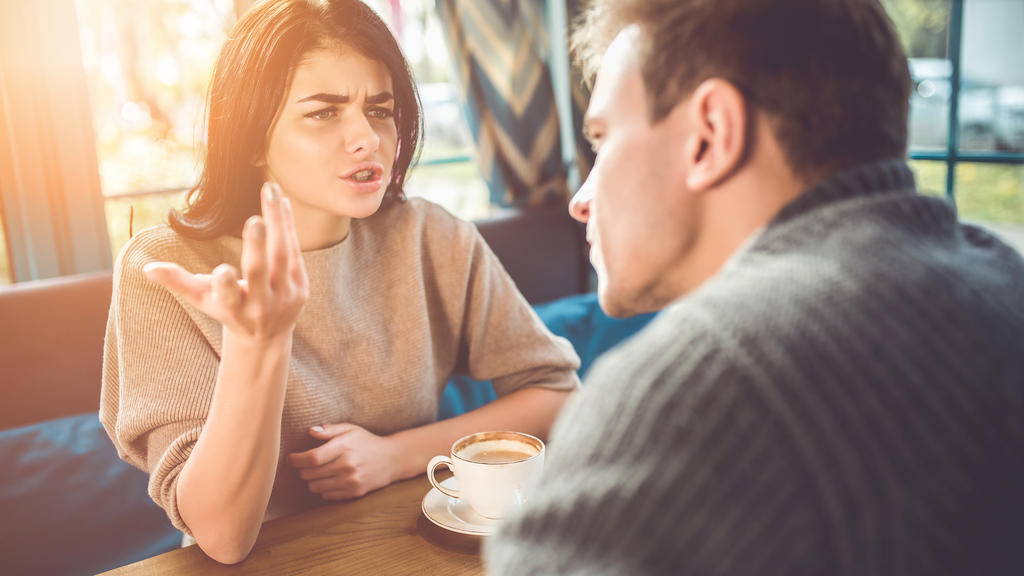 Ein Mann und eine Frau führen in einem Café ein Streitgespräch.