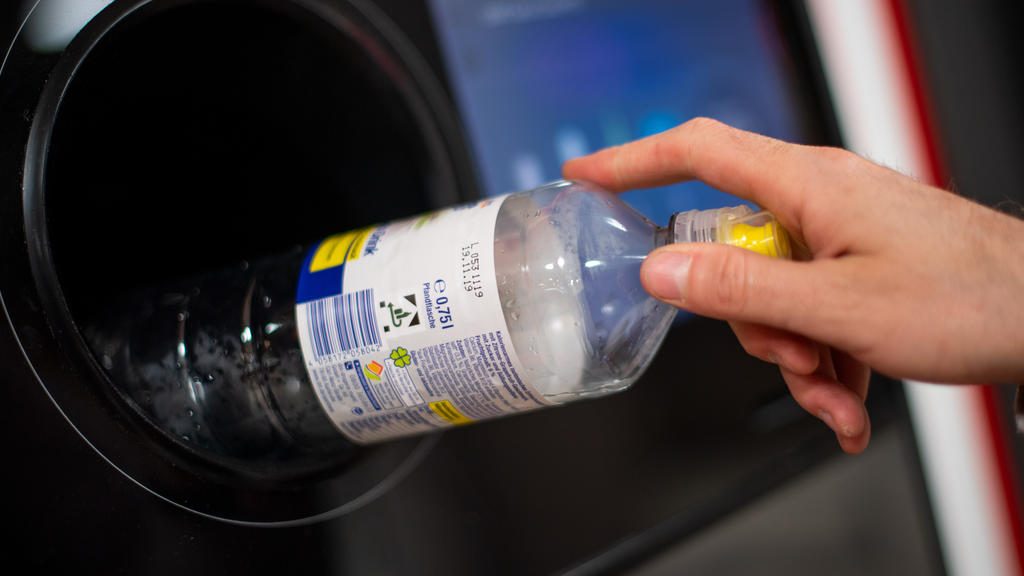 Weibliche Hand wirft Flasche in Pfandautomaten