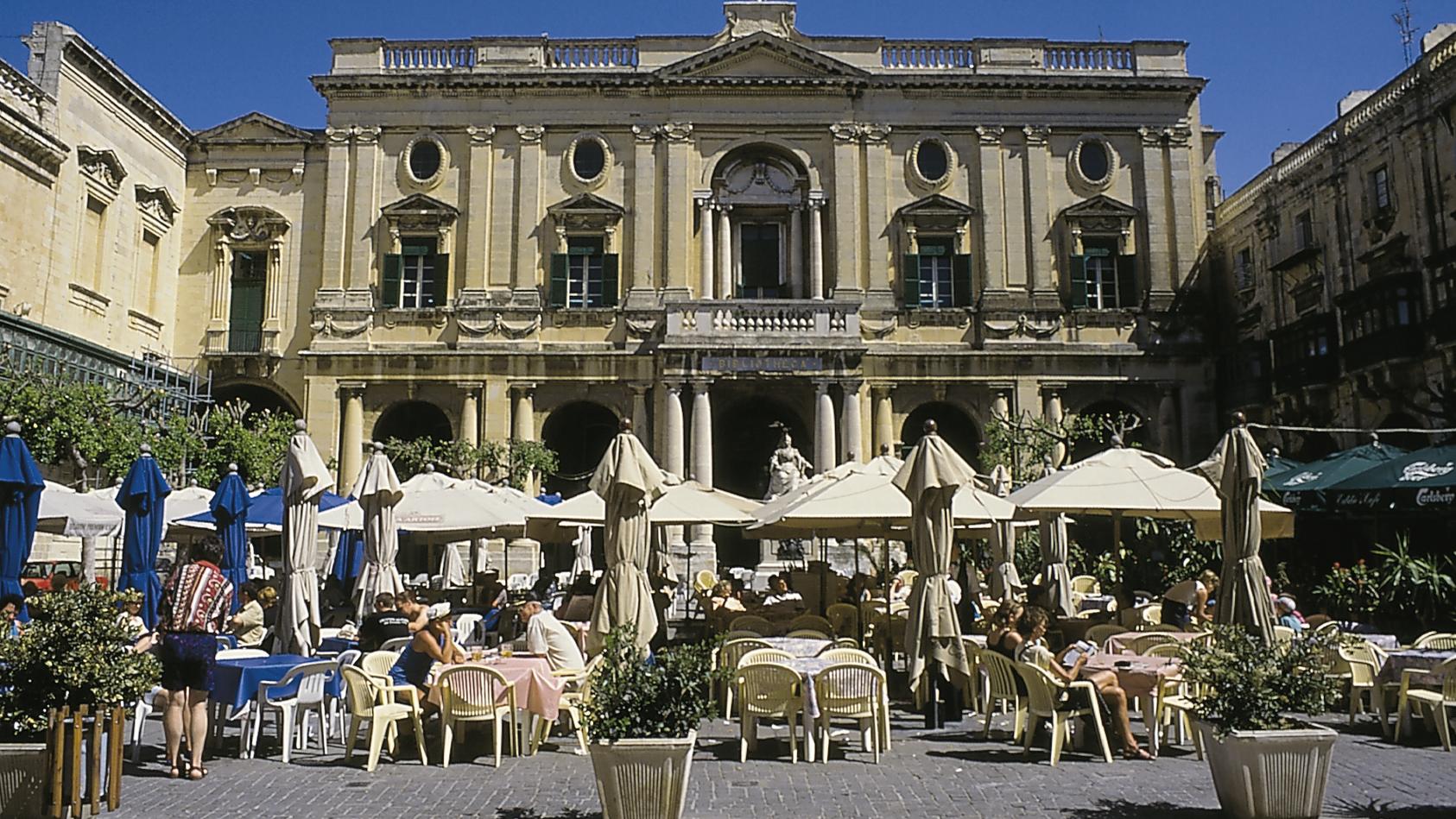 Gebäude der Nationalbibliothek von Malta in La Valetta. Auf dem Vorplatz ein Straßencafé.