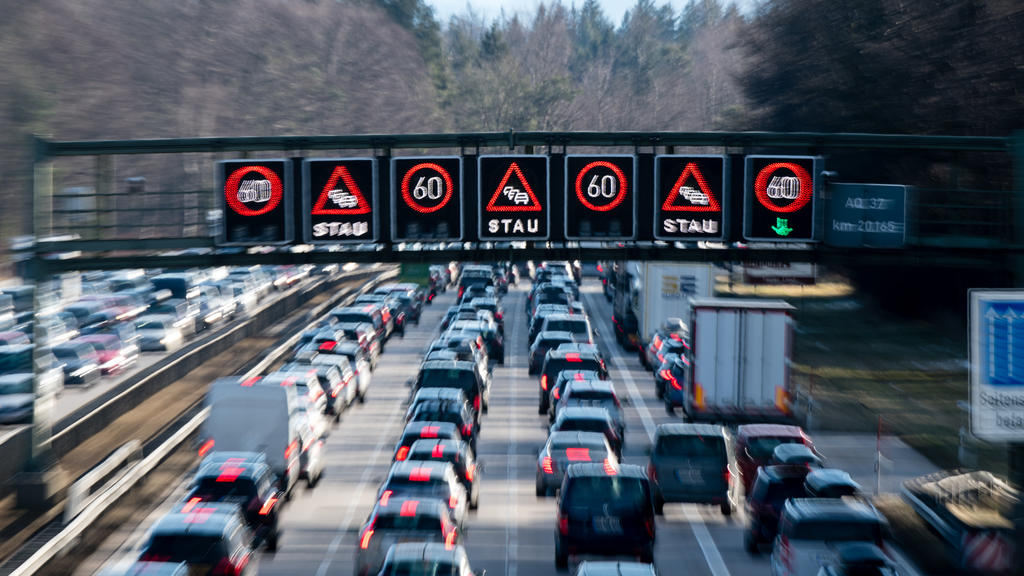ARCHIV - 08.02.2020, Bayern, Sauerlach: Dichter Verkehr schiebt sich über die Autobahn 8 in Fahrtrichtung Salzburg und Brenner-Autobahn im Hofoldinger Forst, während über der Straße auf einer digitalen Anzeige vor Stau gewarnt wird. (zu dpa "ADAC