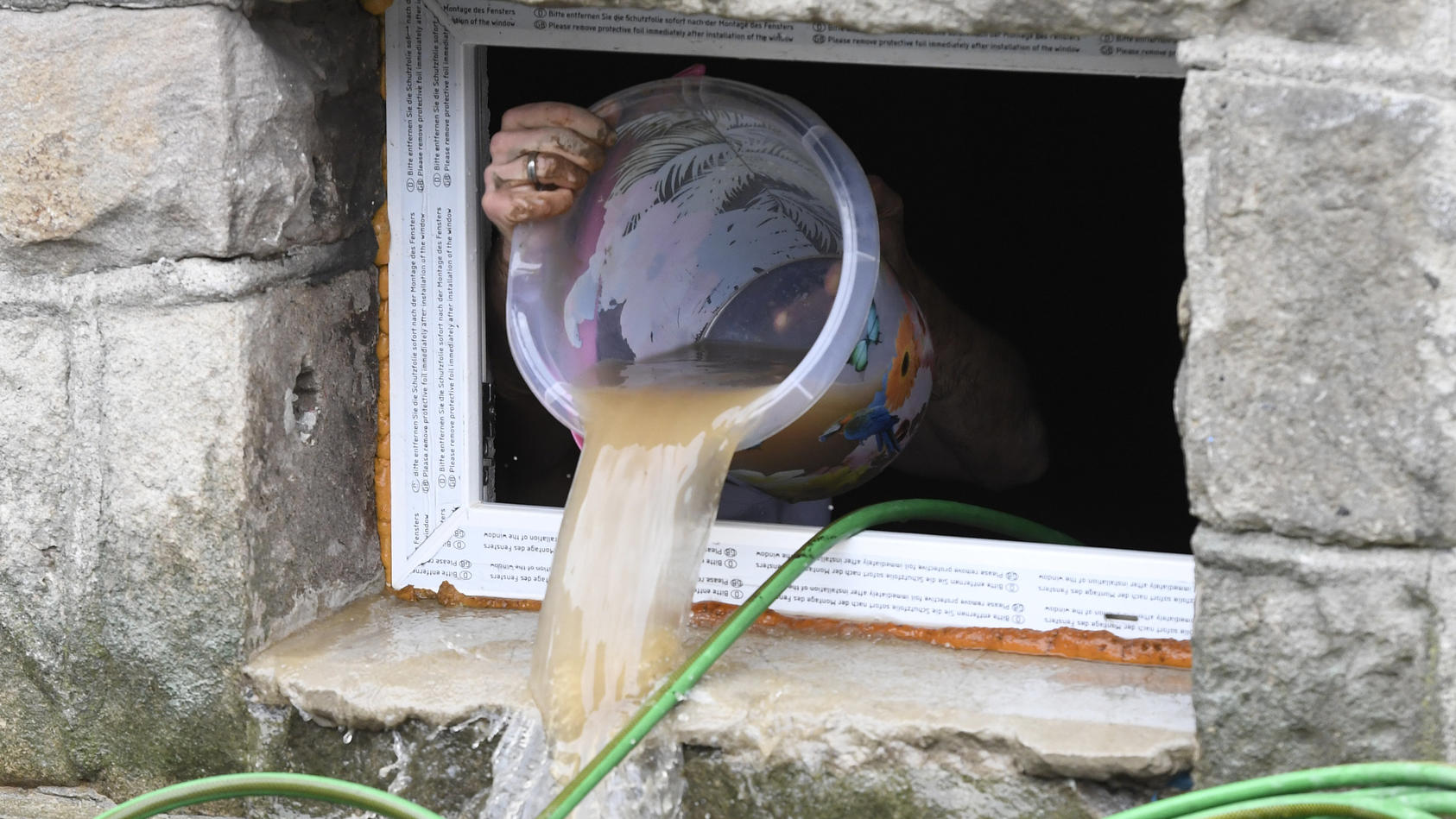 Nordrhein-Westfalen, Hagen: Ein Anwohner beseitigt seine Schäden im Keller, in dem er kurzerhand das Wasser mit einem Eimer aus dem Keller befördert.