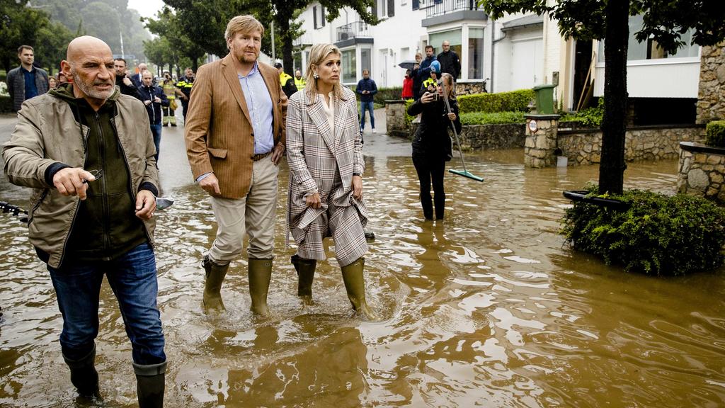 Willem-Alexander und Máxima wirken deutlich betroffen, als sie mit Gummistiefeln durch das knöchelhohe Wasser in Valkenburg waten.