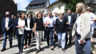 18.07.2021, Rheinland-Pfalz, Schuld: Bundeskanzlerin Angela Merkel (4.v.r) und Malu Dreyer (4.v.l, SPD), Ministerpräsidentin von Rheinland-Pfalz, gehen bei ihrem Besuch durch die Innenstadt von Schuld, um die Schäden von dem Hochwasser zu begutachten und mit Betroffenen zu sprechen. Foto: Christof Stache/POOL AFP/dpa +++ dpa-Bildfunk +++