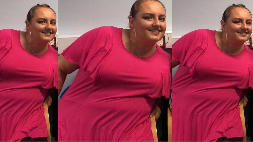 Eine Frau posiert in einem pinken Shirt und ist stark übergewichtig.