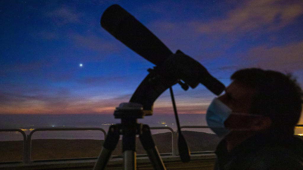 Man watches a conjunction between Jupiter and Saturn seen above Split, after sunset , in Split, Croatia,on December 21, 2020. This event, known as a great conjunction, happens about once every 20 years.But the closeness of the two planets makes thi