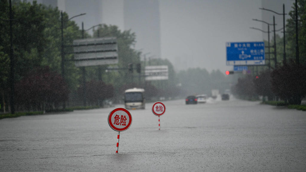 210720 -- ZHENGZHOU, July 20, 2021 -- Danger signs are installed on a waterlogged road in Zhengzhou, capital of central China s Henan Province, July 20, 2021. More than 144,660 residents have been affected by torrential rains in central China s Hena