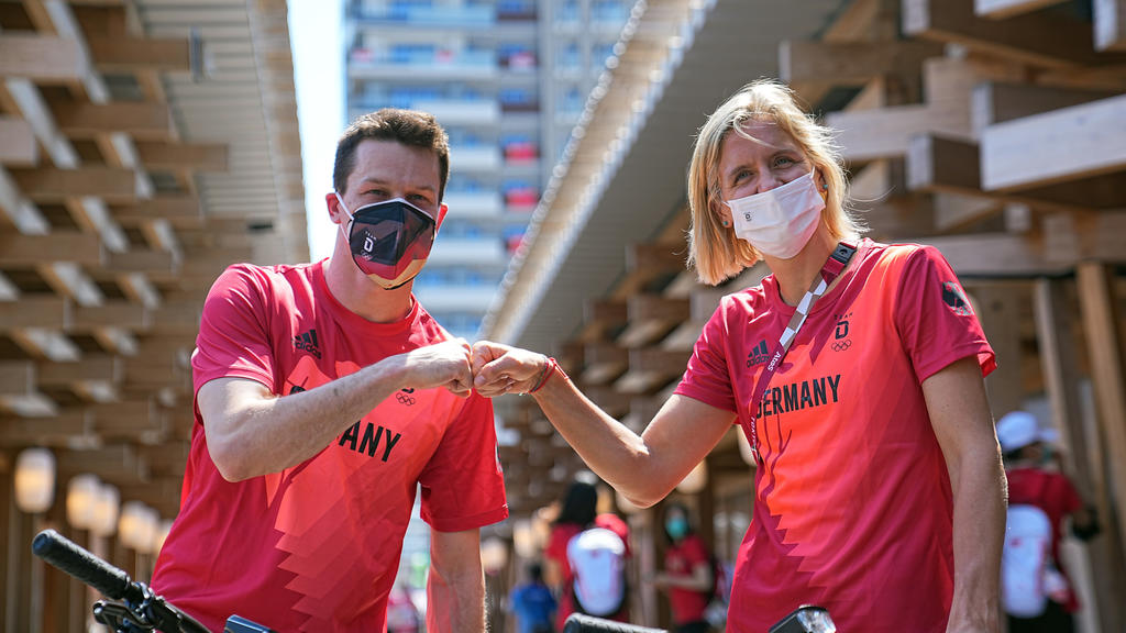 dpatopbilder - 22.07.2021, Japan, Tokio: Wasserspringer Patrick Hausding (l) und Beachvolleyballspielerin Laura Ludwig begrüßen sich vor der Pressekonferenz vom Deutschen Olympischen Sportbund (DOSB) zur Vorstellung des Fahnenträger-Duos vom Team Deu