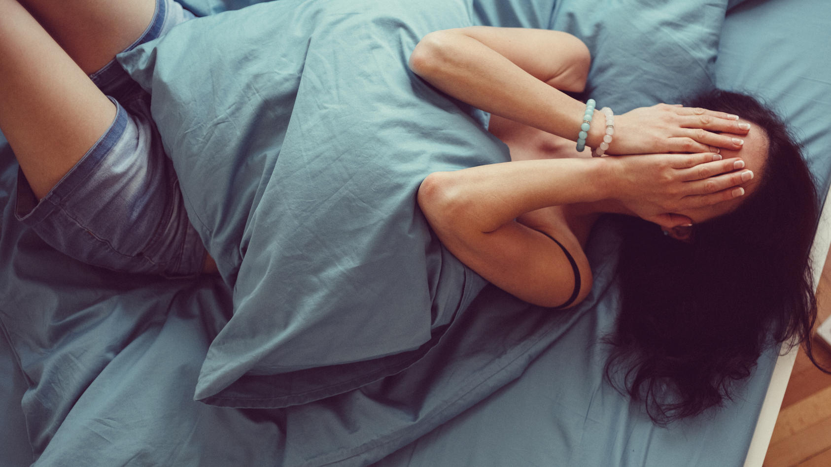 Depressed woman in bed with hands on face