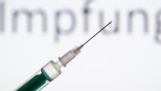 Eine Spritze wird vor den Schriftzug «Impfung» gehalten
