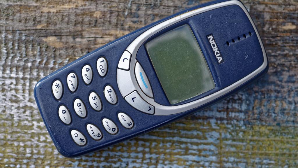 Ein Nokia 3310-Handy liegt auf einem Holz-Untergrund.