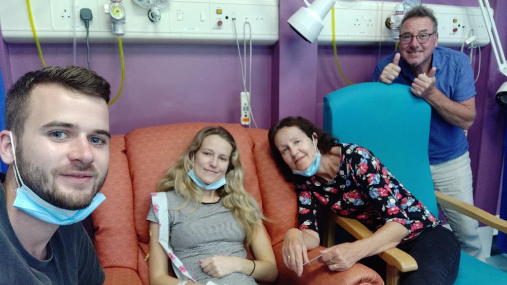 Die kranke Kate sitzt im Krankenhaus auf einem Sofa, umgeben von ihrem Verlobten Ryan und ihren Eltern.