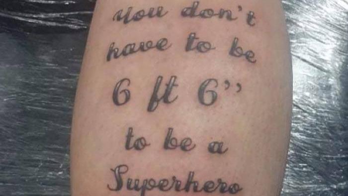 Das Tattoo auf Kevs Wade zeigt Vater und Sohn sowie den Spruch "Du musst keine zwei Meter groß sein, um ein Superheld zu sein".