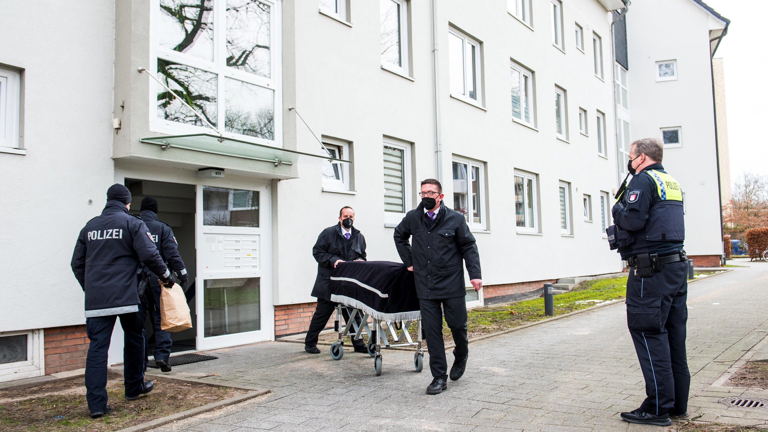 ARCHIV - 08.02.2021, Hamburg: Bestatter transportieren im Februar im Hamburger Stadtteil Bramfeld einen Sarg aus einem Mehrfamilienhaus ab. Ein Mann soll dort am vorherigen Abend seine Mutter umgebracht haben. Etwa einen Tag zuvor soll er auch seine 