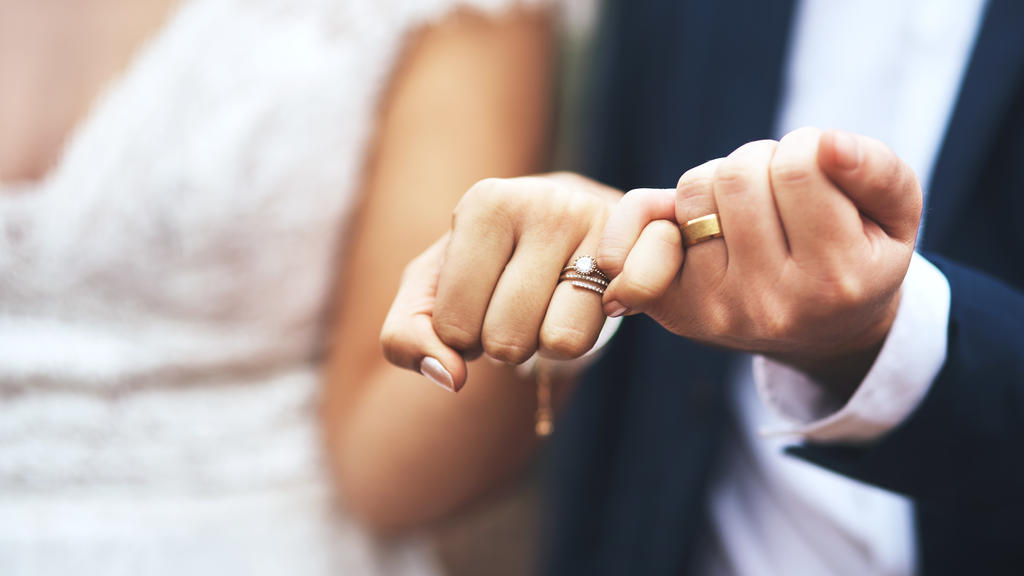 Ein frisch vermähltes Hochzeitspaar zeigt seine Ringe.