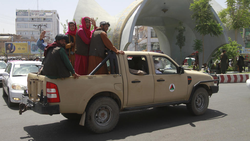 Taliban-Kämpfer sitzen auf der Ladefläche eins Pick-ups. 