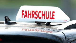 ARCHIV - 13.04.2018, Göttingen: Ein Schild mit der Aufschrift «Fahrschule» ist auf einem Fahrschulauto befestigt. (zu dpa: «Fahrlehrer beklagen Terminmangel für Führerscheinprüfungen») Foto: Swen Pförtner/dpa +++ dpa-Bildfunk +++