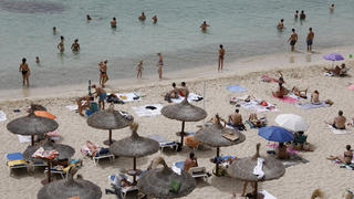 10.08.2021, Spanien, Calvia: Menschen sonnen sich am Strand von Puerto Portals. Foto: Clara Margais/dpa +++ dpa-Bildfunk +++
