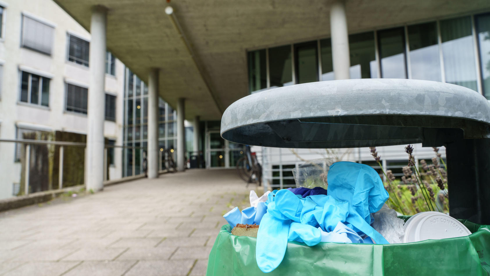24.08.2021, Hessen, Darmstadt: Benutzte Einweg-Handschuhe liegen in einem Abfallbehälter vor dem Gebäude L201 auf dem Campus Lichtwiese der Technischen Universität (TU) Darmstadt. Am Tag zuvor waren hier sechs Menschen mit Vergiftungserscheinungen in