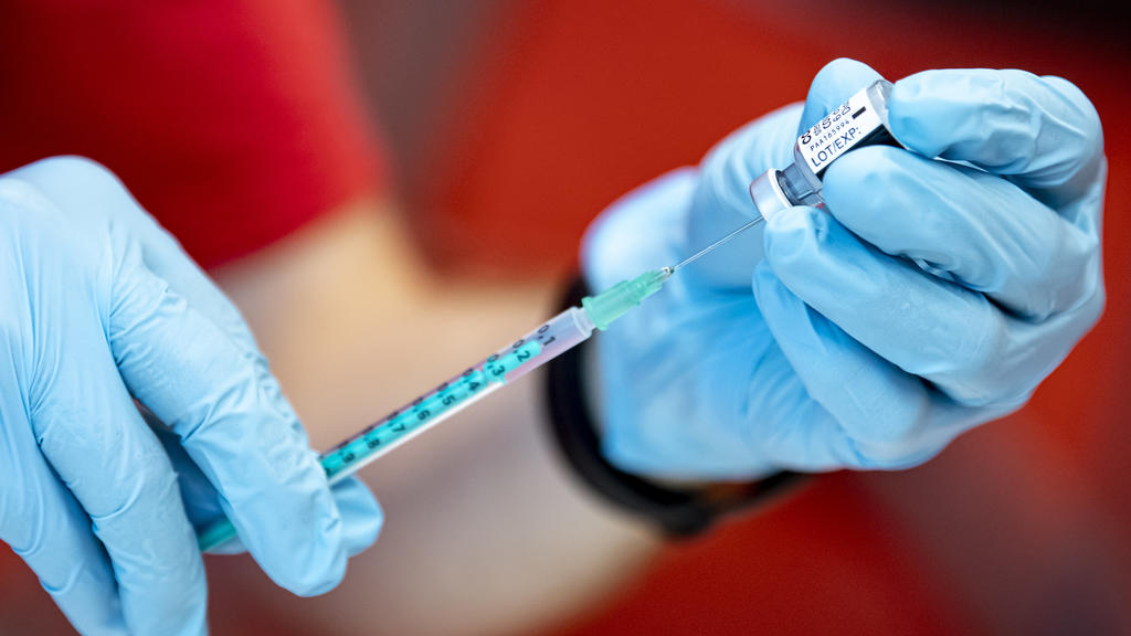 Eine Notfallsanitäter der DLRG zieht an der Universität Potsdam den Corona-Impfstoff von Biontech in eine Spritze. Auch wenn sich geimpfte Menschen mit dem Coronavirus infizieren, hilft die Spritze dennoch.