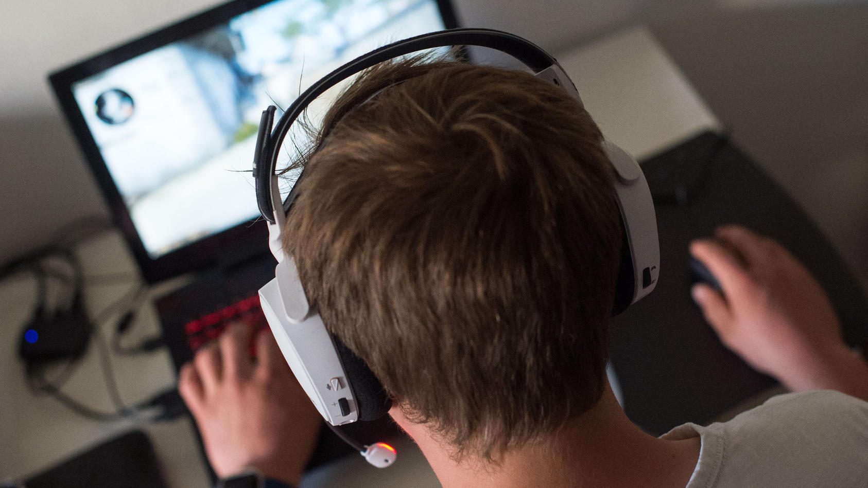 ein-mann-sitzt-am-mit-einem-headset-vor-einem-laptop-und-spielt-ein-online-computerspiel-symbolbild