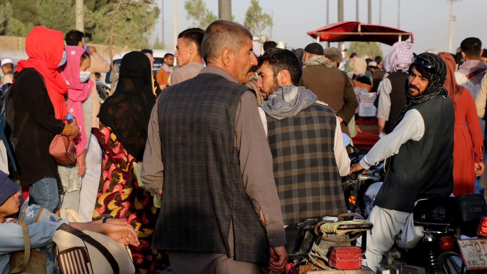 Mehrere Afghanen laufen auf einer Straße umher.