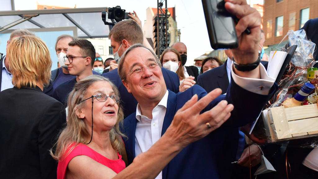03.09.2021, Thüringen, Erfurt: Armin Laschet, CDU-Kanzlerkandidat, CDU-Bundesvorsitzender und Ministerpräsident von Nordrhein-Westfalen, und Martina Krebs aus Erfurt stehen für ein Selfie nebeneinander auf dem Anger während einer Wahlkampfveranstaltu