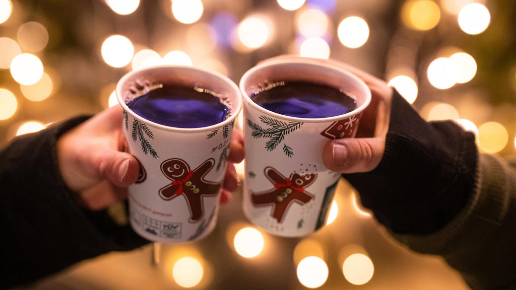 ARCHIV - 07.12.2020, Baden-Württemberg, Stuttgart: Zwei Frauen stoßen mit Glühwein gefüllten Bechern auf dem Weihnachtsmarkt an. (zu dpa «Stuttgarts Weihnachtsmarkt noch unsicher - andere Städte planen fest») Foto: Christoph Schmidt/dpa +++ dpa-Bildf