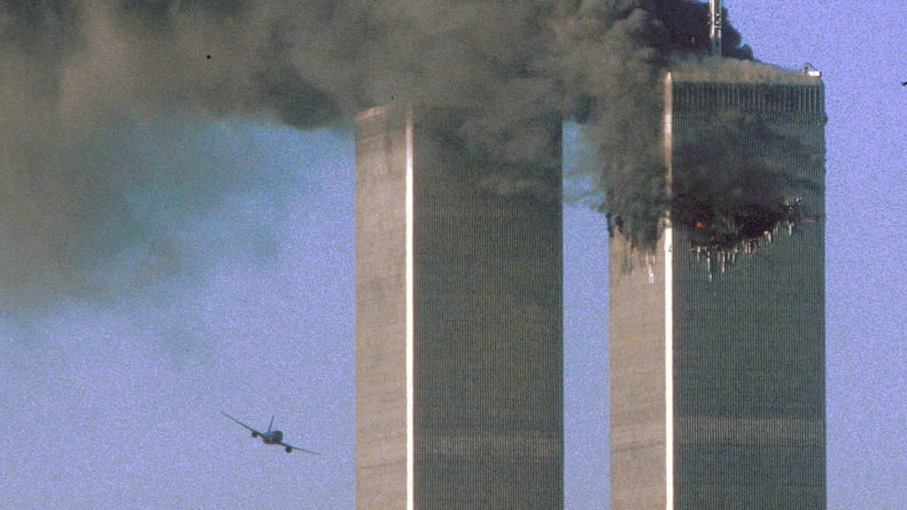 FILE PHOTO: Hijacked United Airlines Flight 175 flies toward the World Trade Center twin towers shortly before slamming into the South tower (L), as the North tower burns, following an earlier attack by a hijacked airliner in New York, U.S., Septembe