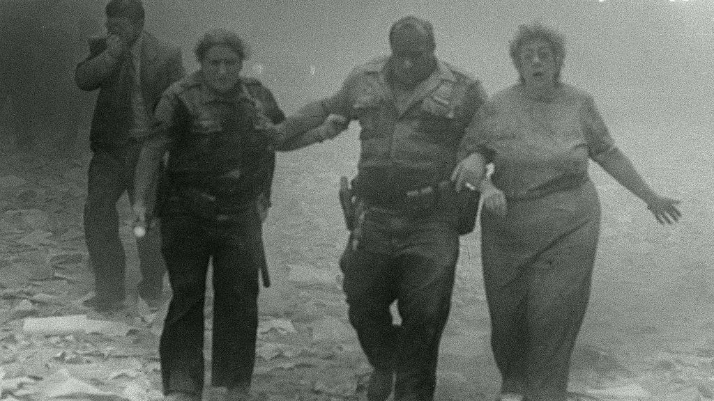 Menschen laufen nach dem Anschlag auf die Twin Tower in New York durch die Trümmerlandschaft, überzogen von weißem Staub.
