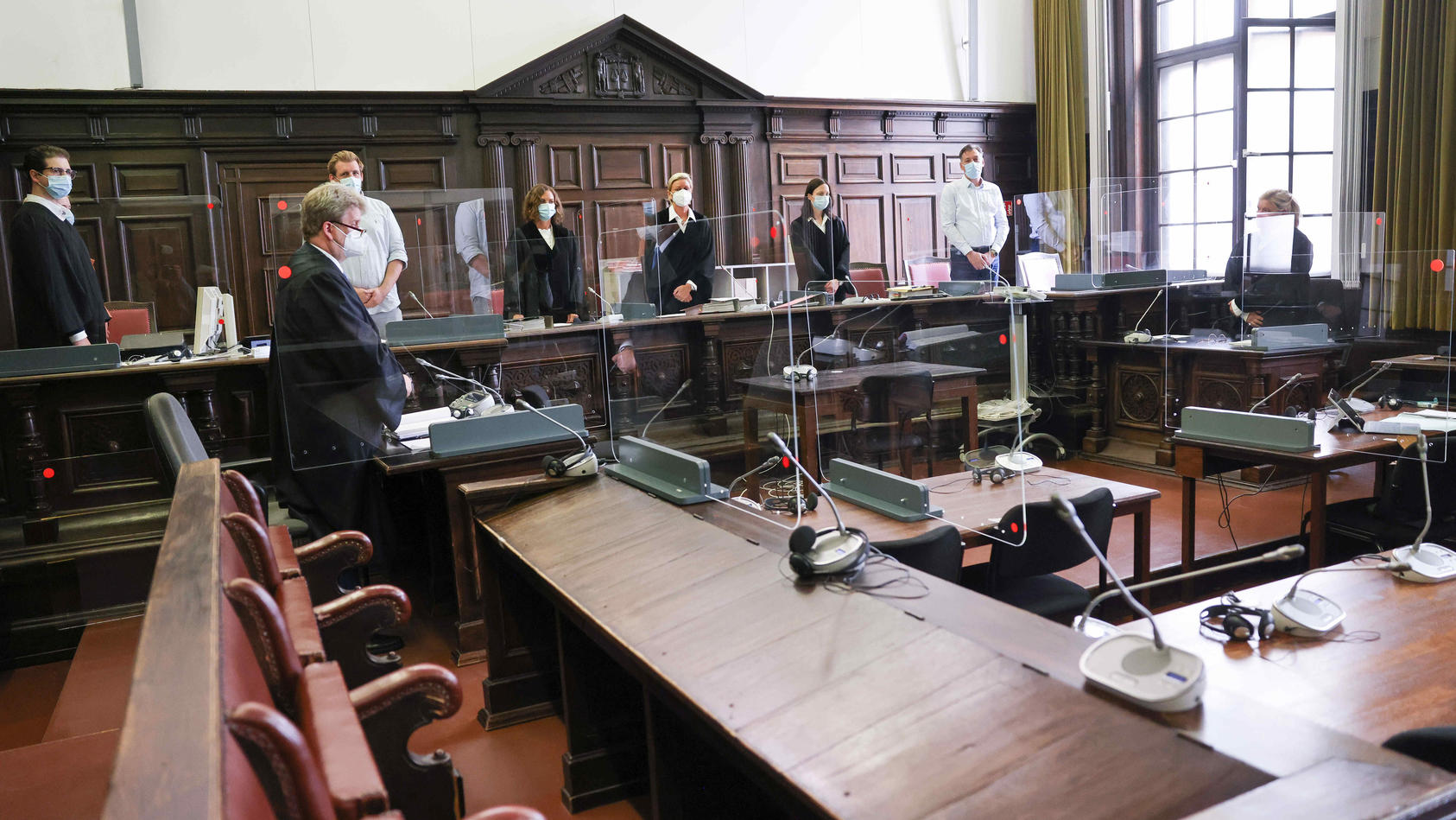 ARCHIV - 03.08.2021, Hamburg: Jessica Koerner (5.v.l), Vorsitzende Richterin am Landgericht, Peter Jacobi (2.v.l), Anwalt des Beschuldigten, und weitere Prozessbeteiligte stehen zu Beginn des ersten Prozesstages im Sitzungssal im Strafjustizgebäude. 