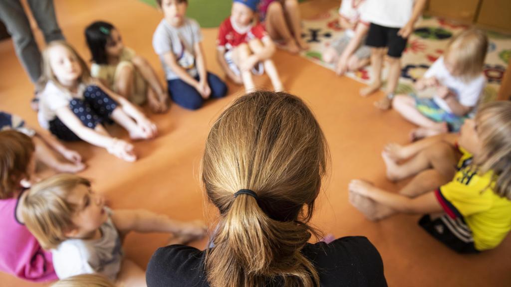 Erzieherin sitzt mit Kindern im Kindergarten im Kreis auf dem Boden, Köln, Nordrhein-Westfalen, Deutschland, Europa *** Educator sits with children in the kindergarten in a circle on the floor, Cologne, North Rhine-Westphalia, Germany, Europe Copyri