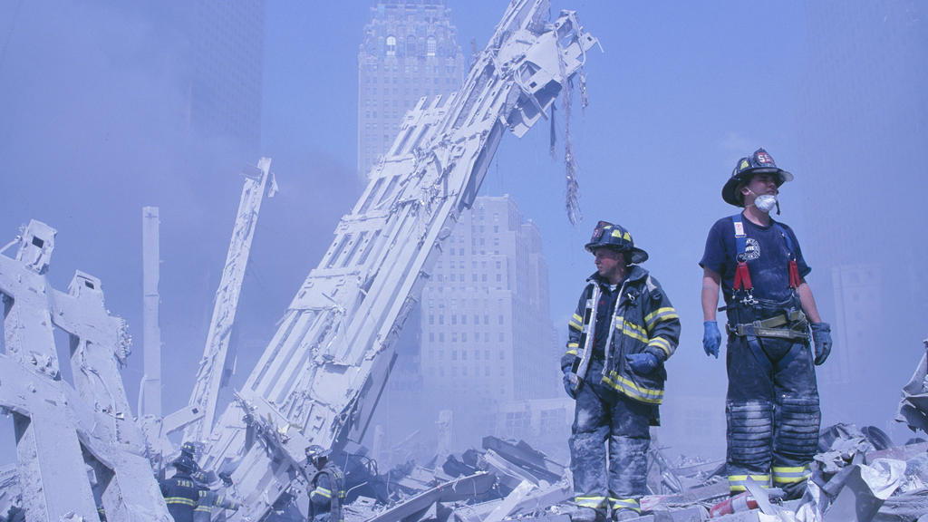 11.09.2001, USA, New York: Feuerwehrleute klettern über die Trümmer des Marriott-Hotels und des in sich zusaamengefallenen zweiten Turms nach dem Terroranschlag auf das World Trade Center. (zu dpa «20 Jahre 9/11: Terroranschläge in den USA») Foto: Ra