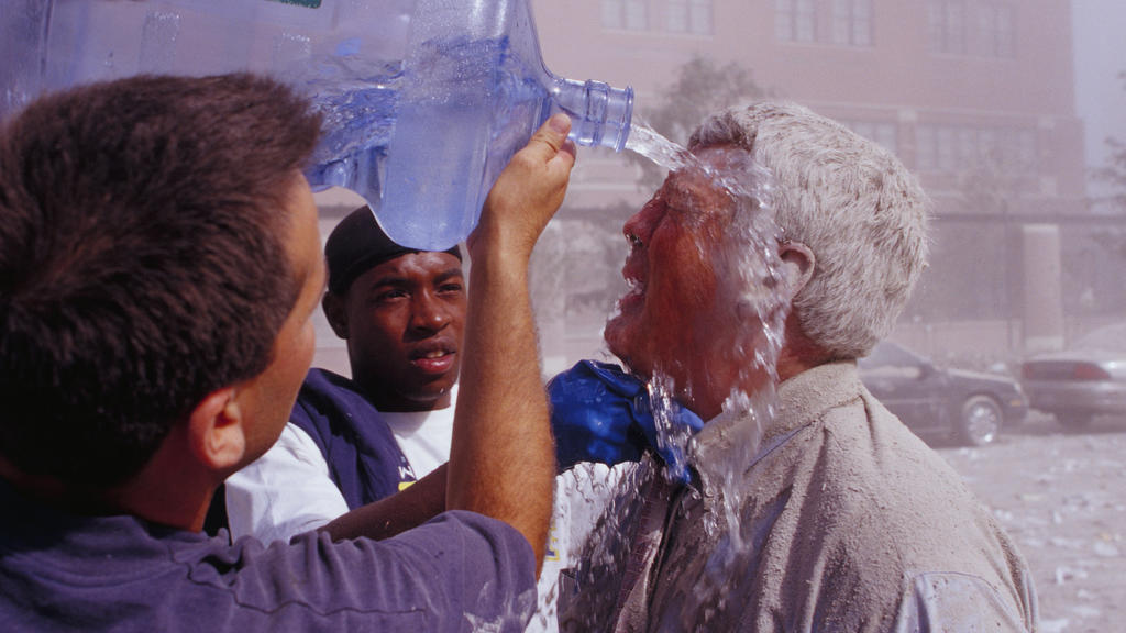 ARCHIV - 11.09.2001, USA, New York: Passanten spülen nach dem Terroranschlag auf das World Trade Center mit Wasser Staub aus dem Gesicht eines Mannes. (zu dpa «20 Jahre 9/11: Terroranschläge in den USA») Foto: Randy Taylor/ZUMA Press Wire Service/dpa
