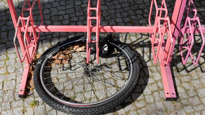 Nur noch das Vorderrad eines Fahrrads ist an einem Fahrradständer angeschlossen. 