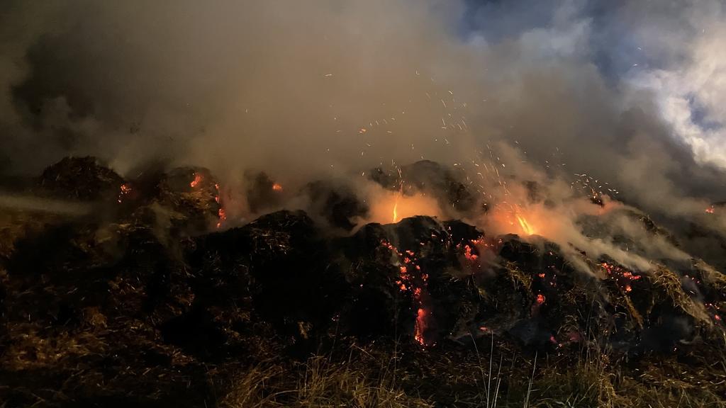 Feuerwehrleute löschen brennende Strohballen