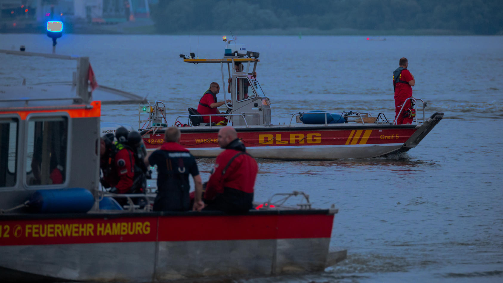 18.06.2021, Hamburg: Kleinboote von DLRG und Feuerwehr fahren bei der Suche über die Elbe. Feuerwehr und Polizei haben am Abend zweieinhalb Stunden nach einem jungen Mann gesucht, der von einem Signalturm in die Elbe gesprungen und nicht mehr aufgeta