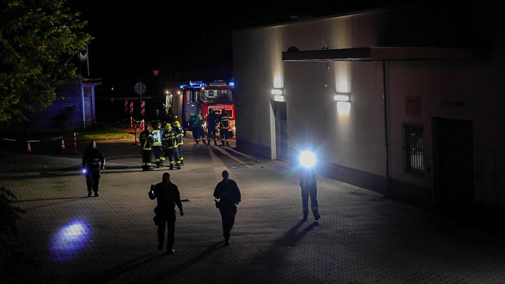 Mit Taschenlampen such Polizeibeamte das Areal um das Impfzentrum in Eich nach Spuren ab.