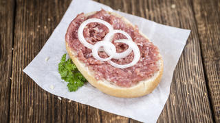 German Cuisine (bun with Mett; selective focus) on wooden background (detailed close-up shot)