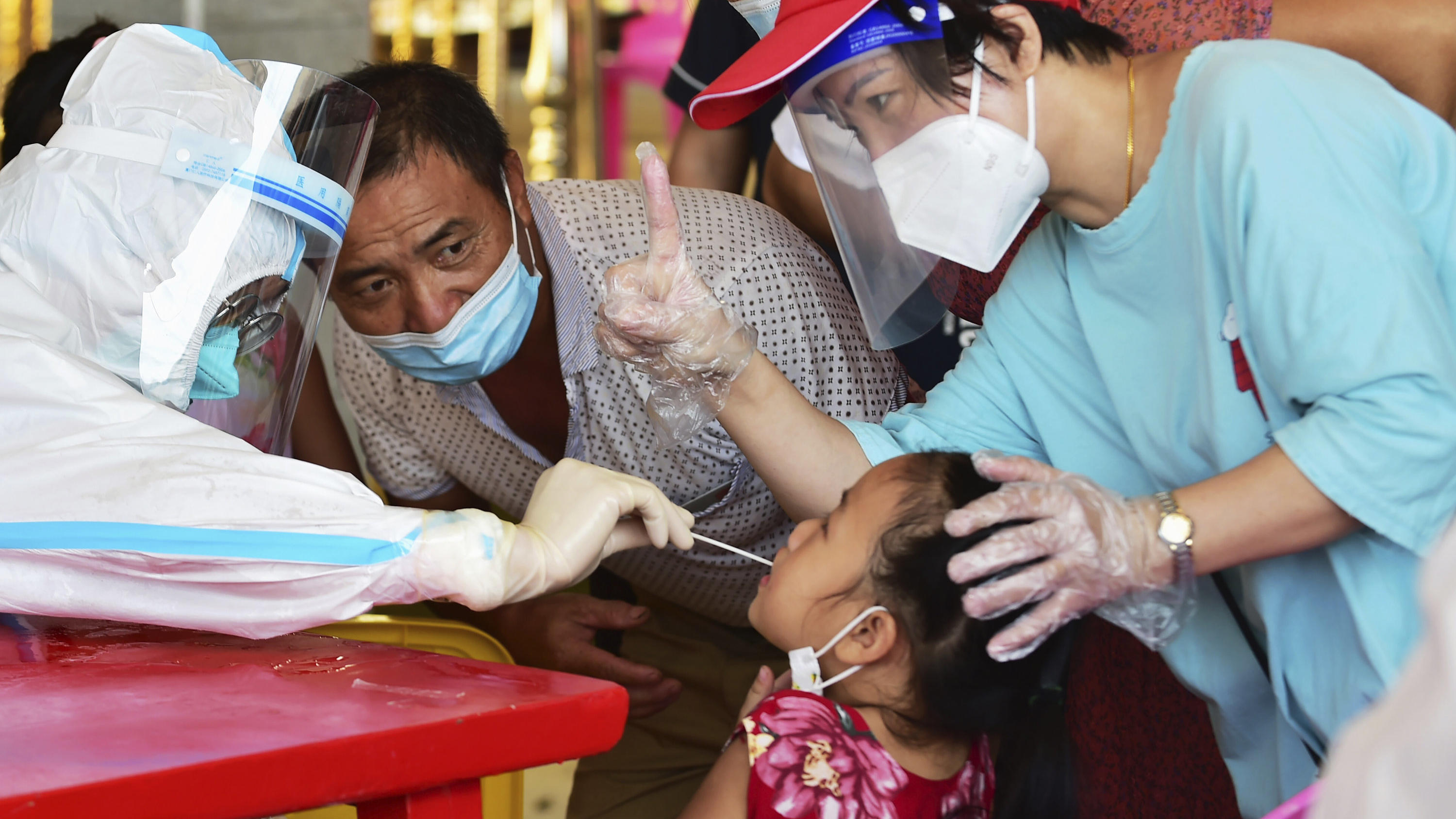 In this photo released by Xinhua News Agency, a health worker collects swab sample from a girl for nucleic acid testing in Xianyou county, Putian city, southeastern China's Fujian Province Thursday, Sept. 16, 2021. China has reported another 62 cases