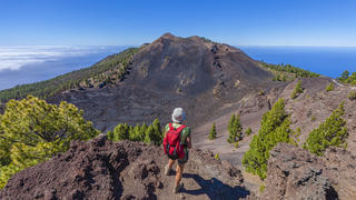 Ein Wanderer steht vor einem Vulkan auf La Palma.