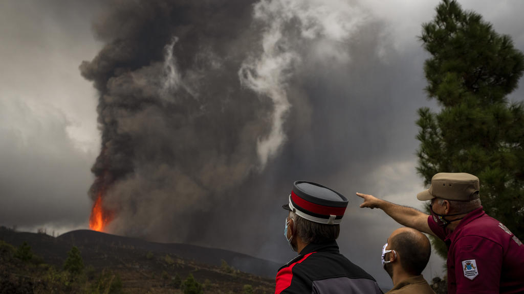 23.09.2021, Spanien, La Palma: Polizeibeamte und Gemeindearbeiter beobachten, wie die Lava während eines Vulkanausbruchs fließt. Der Vulkan in der Cumbre Vieja im Süden der Kanareninsel, der am 19. September 2021 erstmals seit 50 Jahren wieder ausgeb
