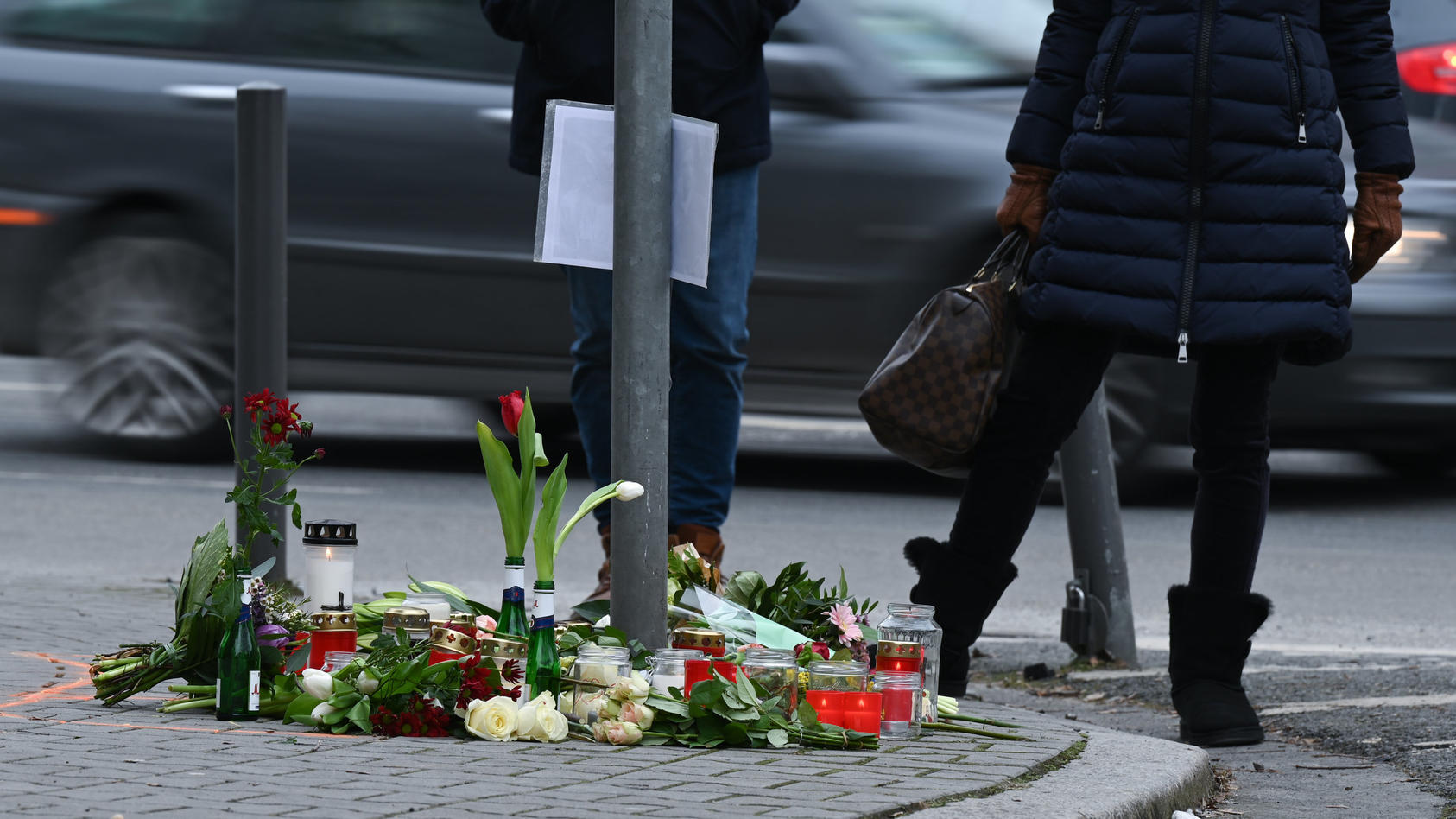 15.02.2021, Hessen, Frankfurt/Main: Menschen trauern an einer Straßenkreuzung im Frankfurter Stadtteil Sachsenhausen, an der Blumen und Kerzen an die Opfer eines tödlichen Verkehrsunfalls vom vergangenen Samstag erinnern. Nach bisherigen Ermittlungen