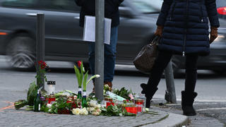 15.02.2021, Hessen, Frankfurt/Main: Menschen trauern an einer Straßenkreuzung im Frankfurter Stadtteil Sachsenhausen, an der Blumen und Kerzen an die Opfer eines tödlichen Verkehrsunfalls vom vergangenen Samstag erinnern. Nach bisherigen Ermittlungen der Polizei waren zwei Fußgänger von einem Pkw erfasst worden, da der Fahrer mit deutlich überhöhter Geschwindigkeit unterwegs war. Foto: Arne Dedert/dpa +++ dpa-Bildfunk +++