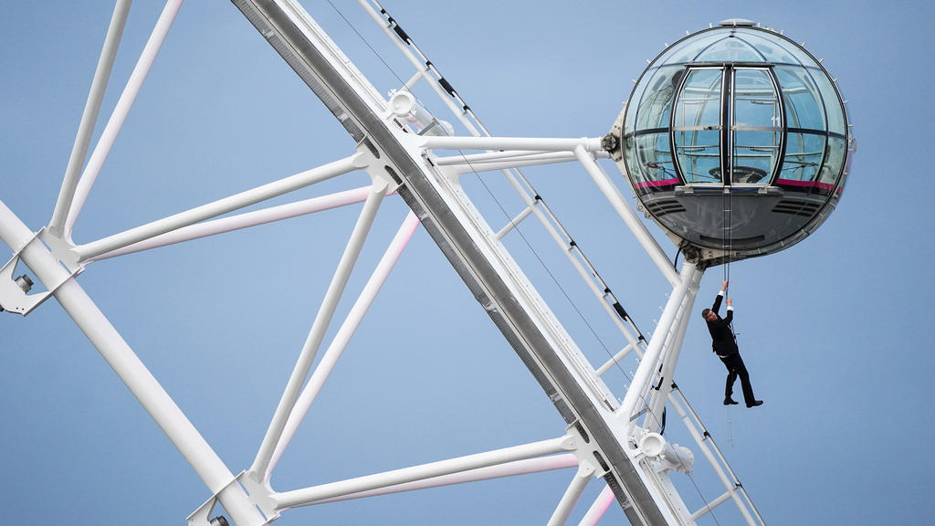 28.09.2021, Großbritannien, London: Ein als Großbritanniens berühmtester Geheimagent James Bond verkleideter Mann hängt an einer Gondel auf dem lastminute.com London Eye, dem Riesenrad im Zentrum Londons, vor der Weltpremiere von No Time To Die, dem 