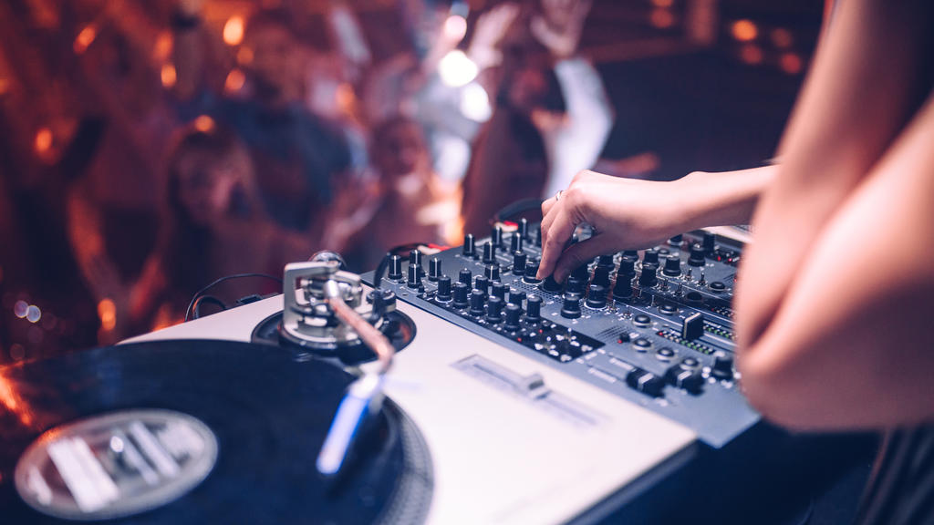 Ein DJ heizt der feiernden Menge auf der Tanzfläche ein.